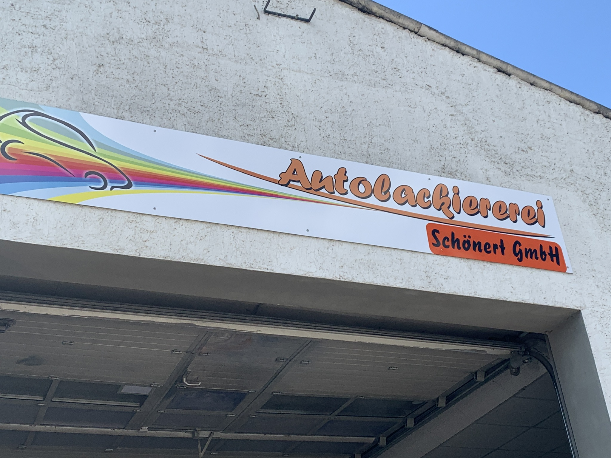 Firmenschild Autolackiererei Schönert GmbH über dem Hallentor